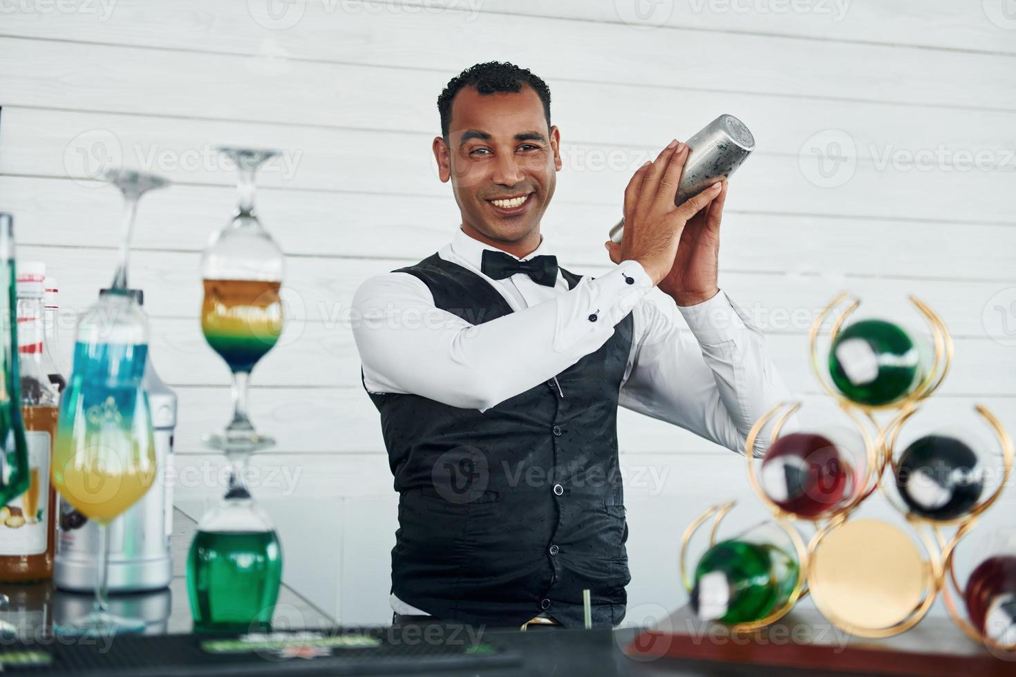 At the bar. Black waiter in formal clothes is at his work outdoors at sunny daytime photo