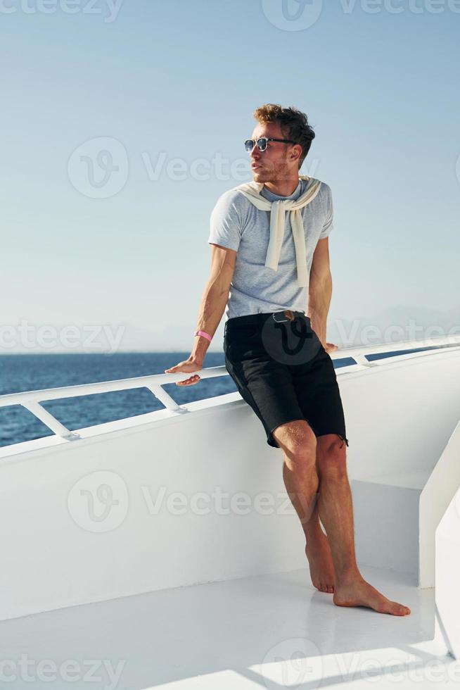 Young male tourist is on the yacht on the sea. Conception of vacation photo