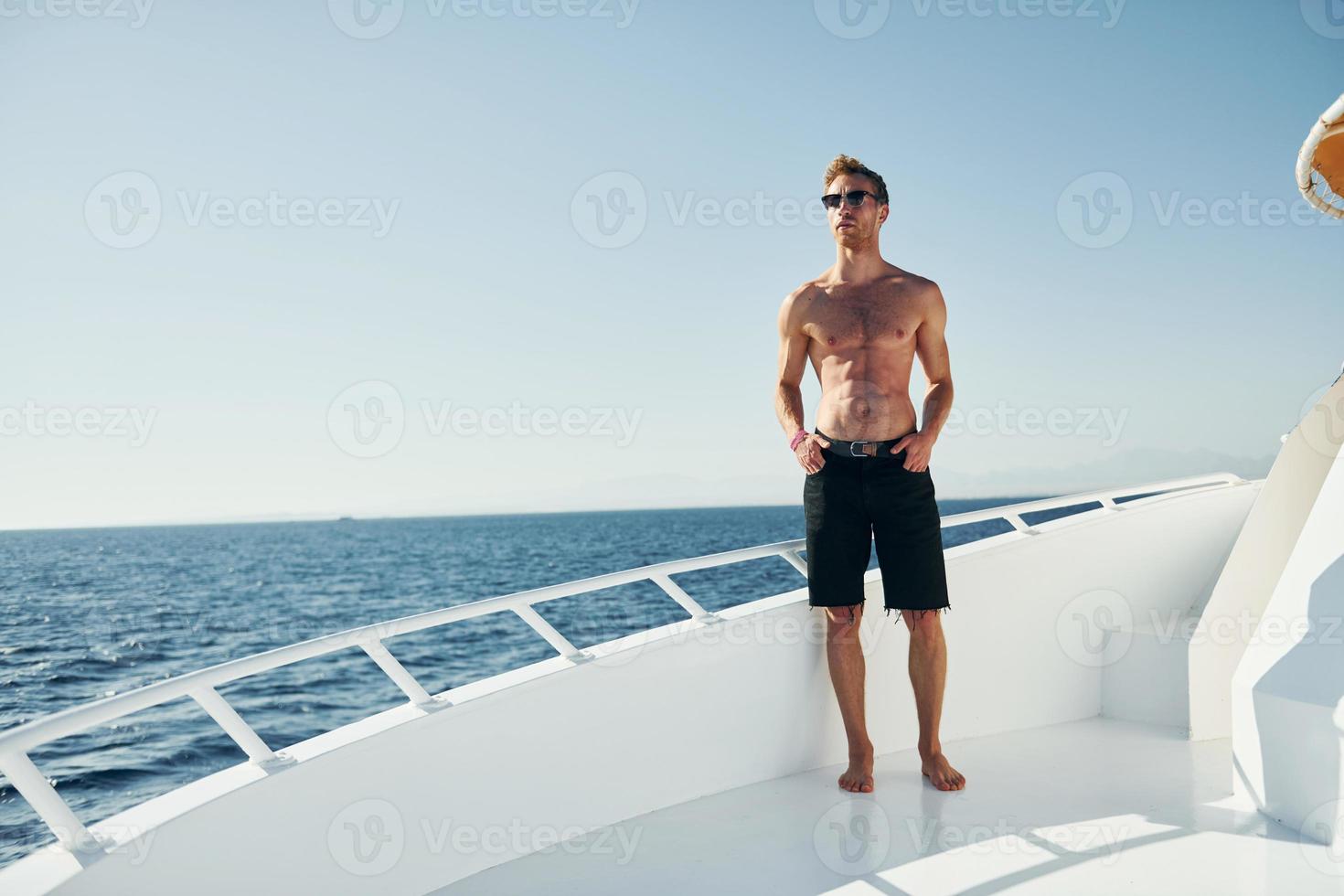 Young male tourist is on the yacht on the sea. Conception of vacation photo