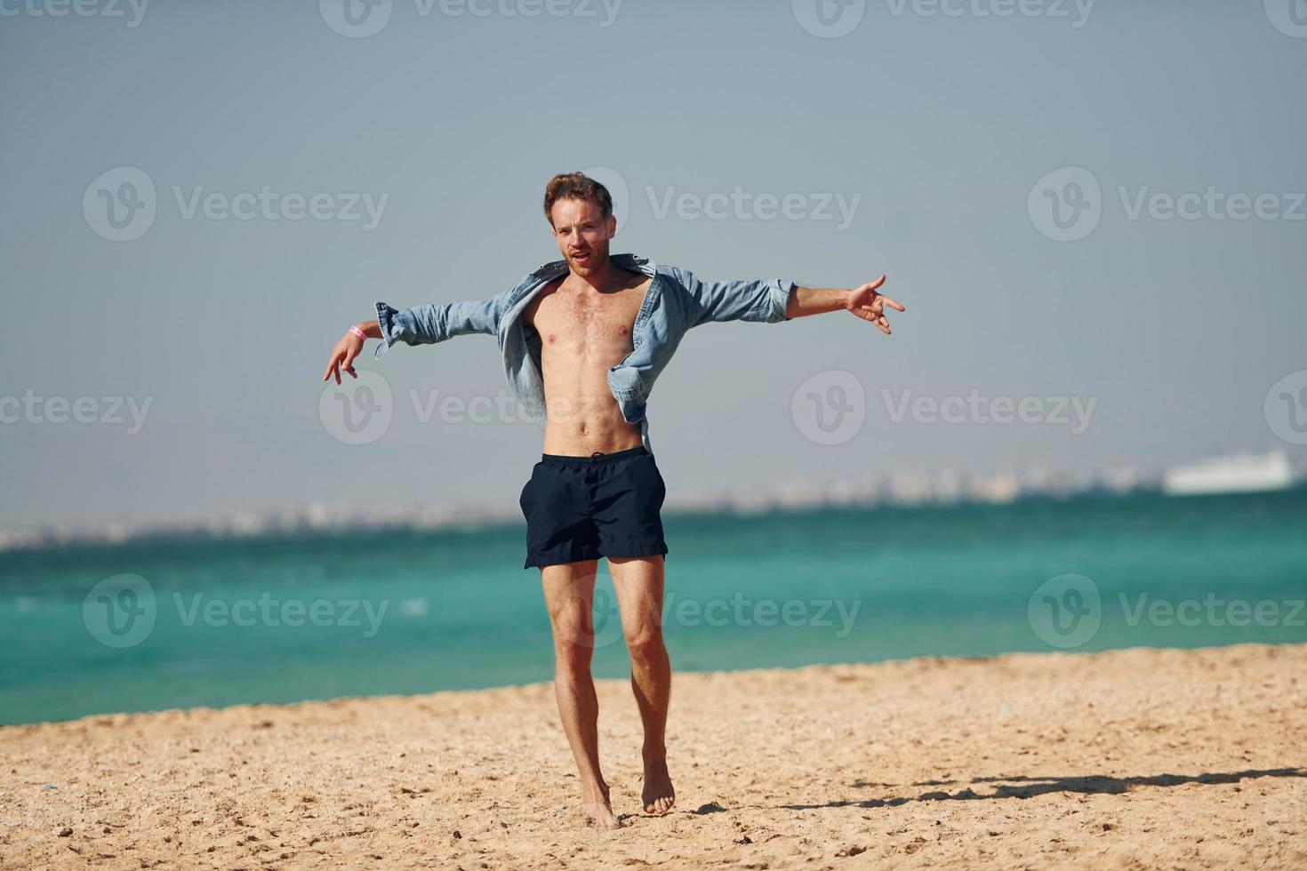 divirtiéndose. joven europeo tiene vacaciones y disfruta del tiempo libre en la playa del mar foto