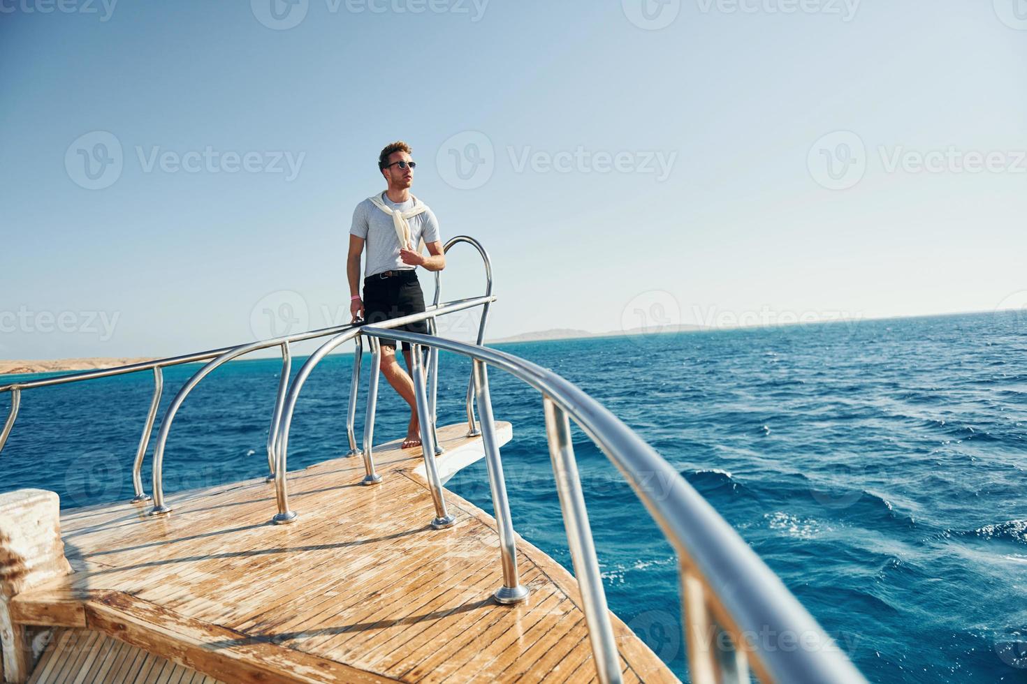 Posing for a camera. Young male tourist is on the yacht on the sea. Conception of vacation photo