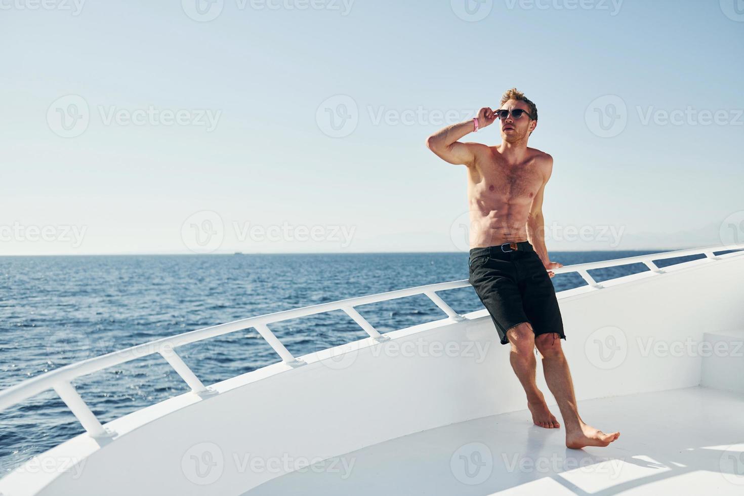 Young male tourist is on the yacht on the sea. Conception of vacation photo