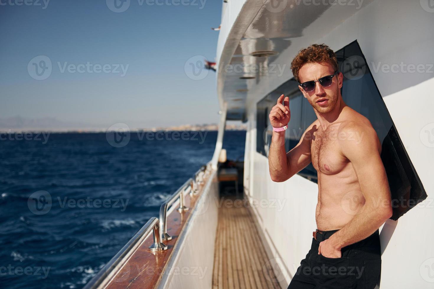 Warm weather. Young male tourist is on the yacht on the sea. Conception of vacation photo