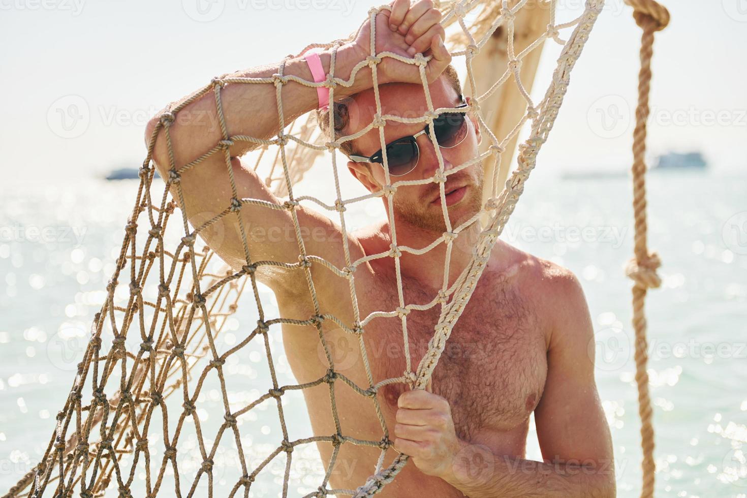Warm weather. Young european man have vacation and enjoying free time on the beach of sea photo