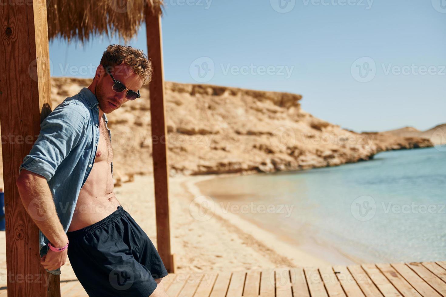 Clear water. Young european man have vacation and enjoying free time on the beach of sea photo