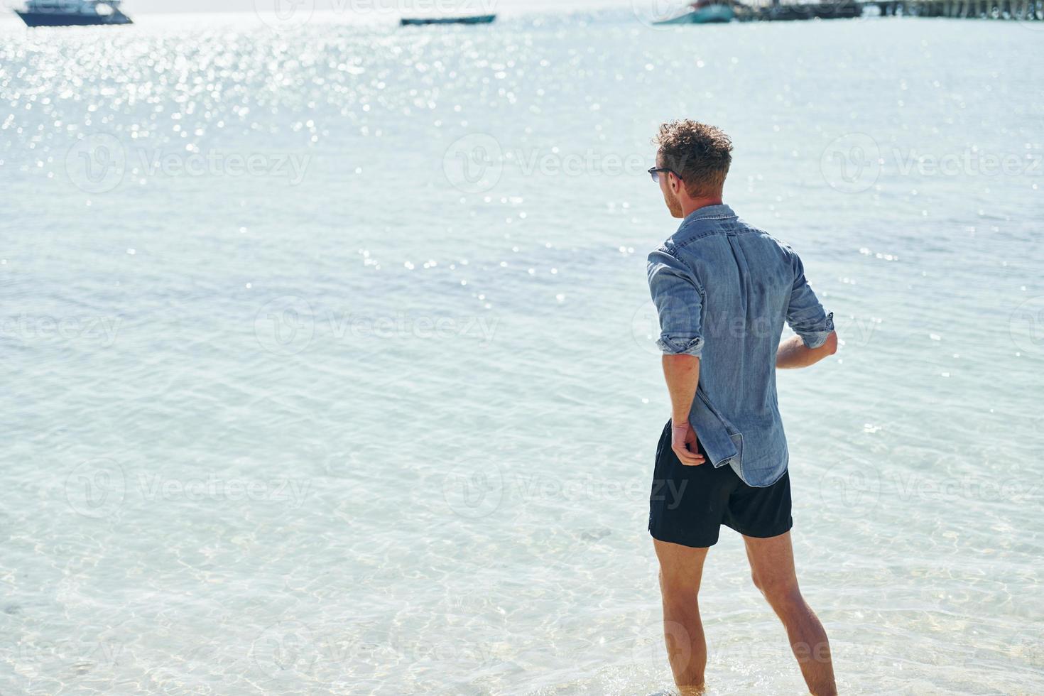 Clear water. Young european man have vacation and enjoying free time on the beach of sea photo