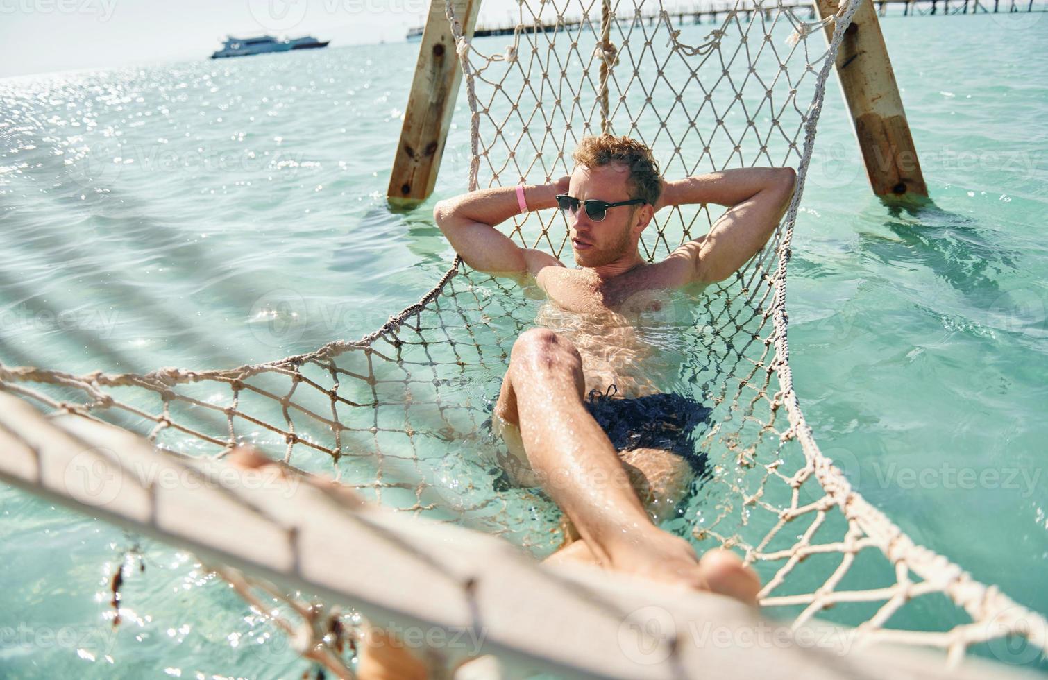 In sunglasses. Young european man have vacation and enjoying free time on the beach of sea photo