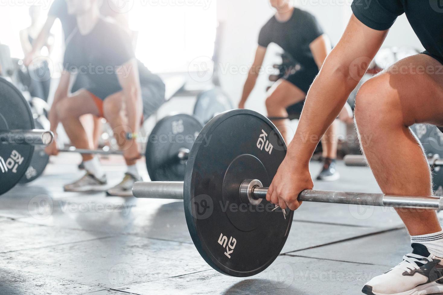 mediante el uso de pesos pesados. grupo de jóvenes deportistas tienen un día de crossfit en el interior del gimnasio foto