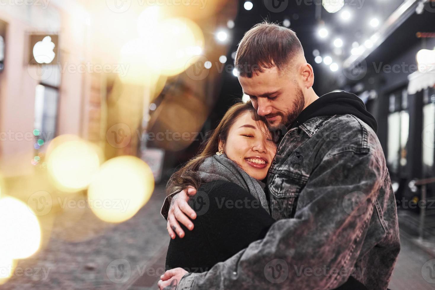 Embracing each other. Happy multiracial couple together outdoors in the city celebrating New year photo