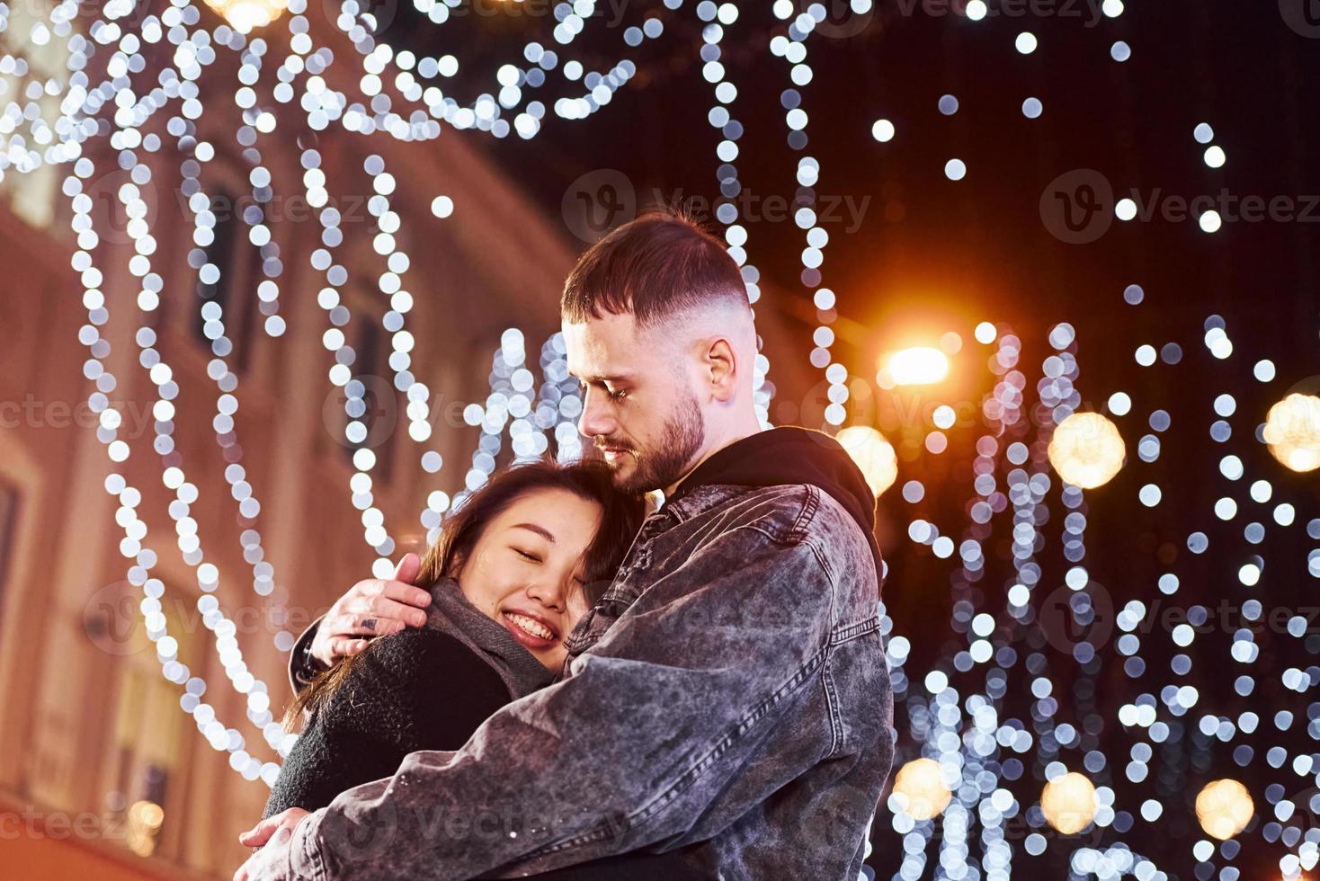 Embracing each other. Happy multiracial couple together outdoors in the city celebrating New year photo