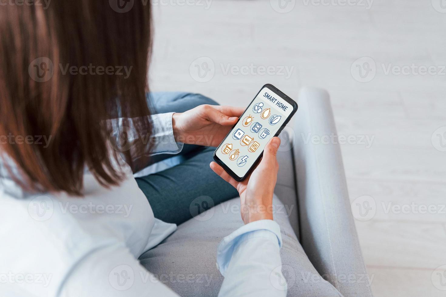 Modern technologies. Rear view of woman that is indoors controlling smart home photo