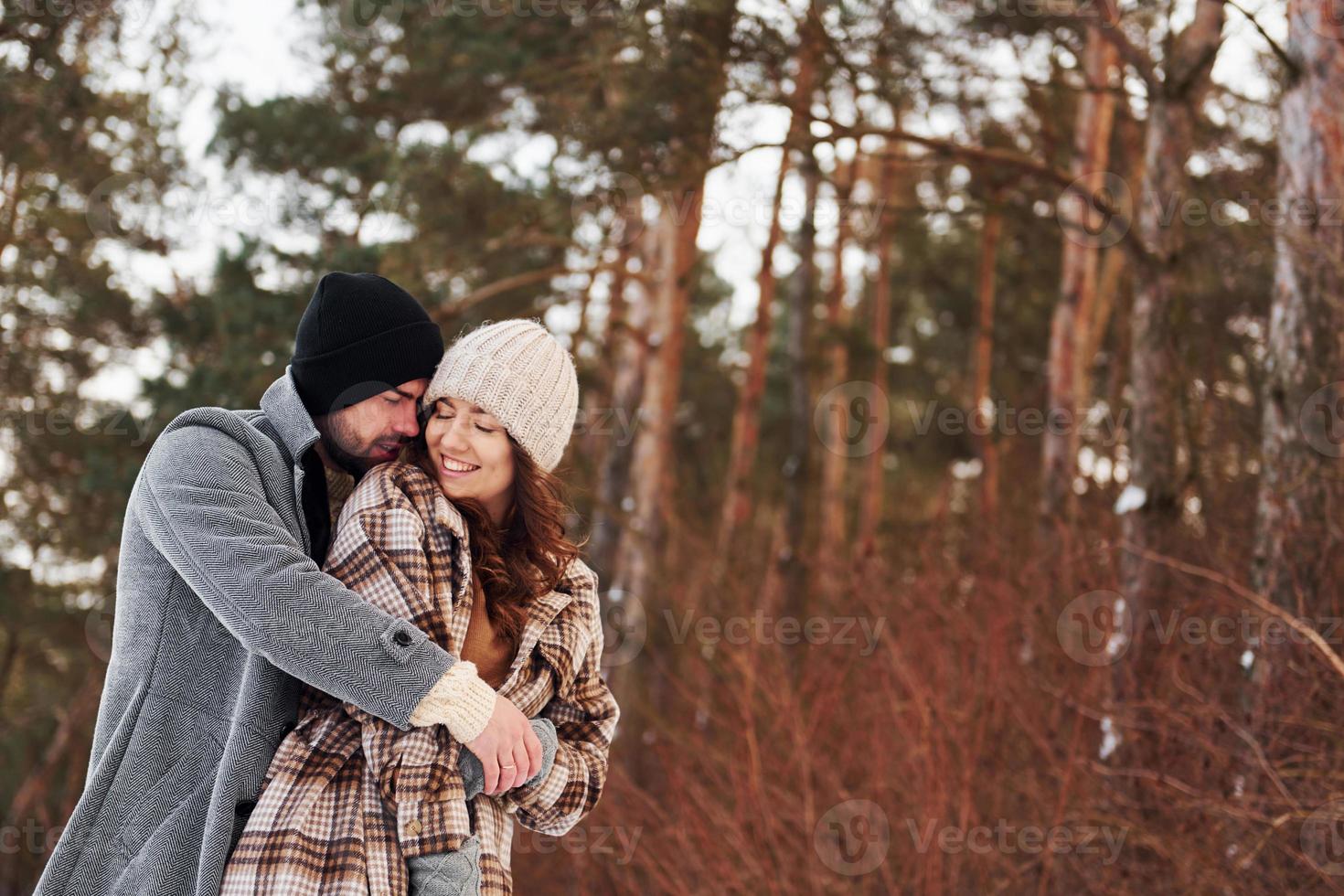 Cheerful couple have a walk in the winter forest at daytime photo