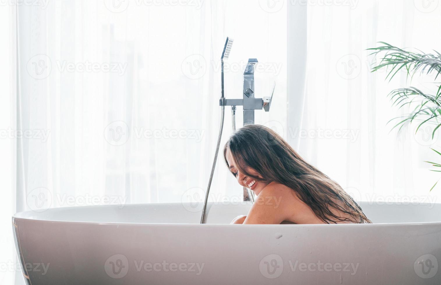 bella joven tiene tiempo libre en casa en el baño foto