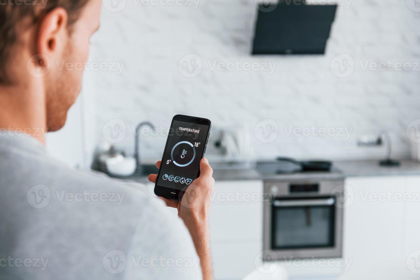 Rear view of adult man that is indoors controlling smart home technology photo