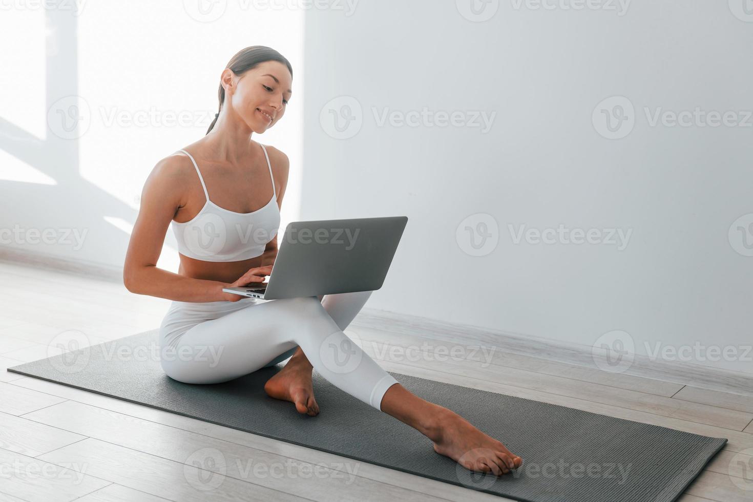 On yoga mat. Young caucasian woman with slim body shape is indoors at  daytime 15363172 Stock Photo at Vecteezy