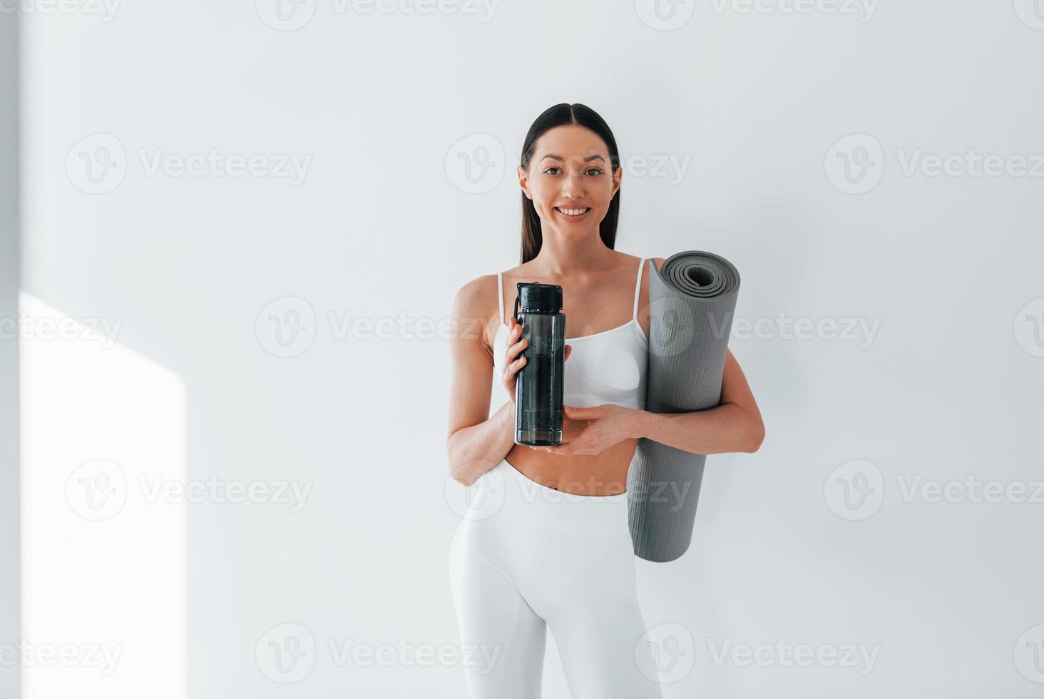 On yoga mat. Young caucasian woman with slim body shape is indoors at  daytime 15363172 Stock Photo at Vecteezy