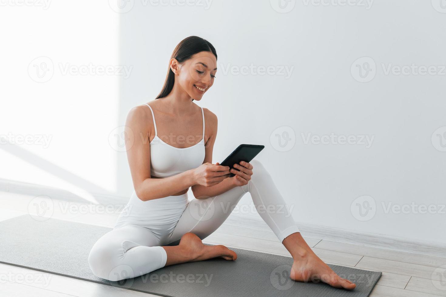 On yoga mat. Young caucasian woman with slim body shape is indoors at  daytime 15363172 Stock Photo at Vecteezy