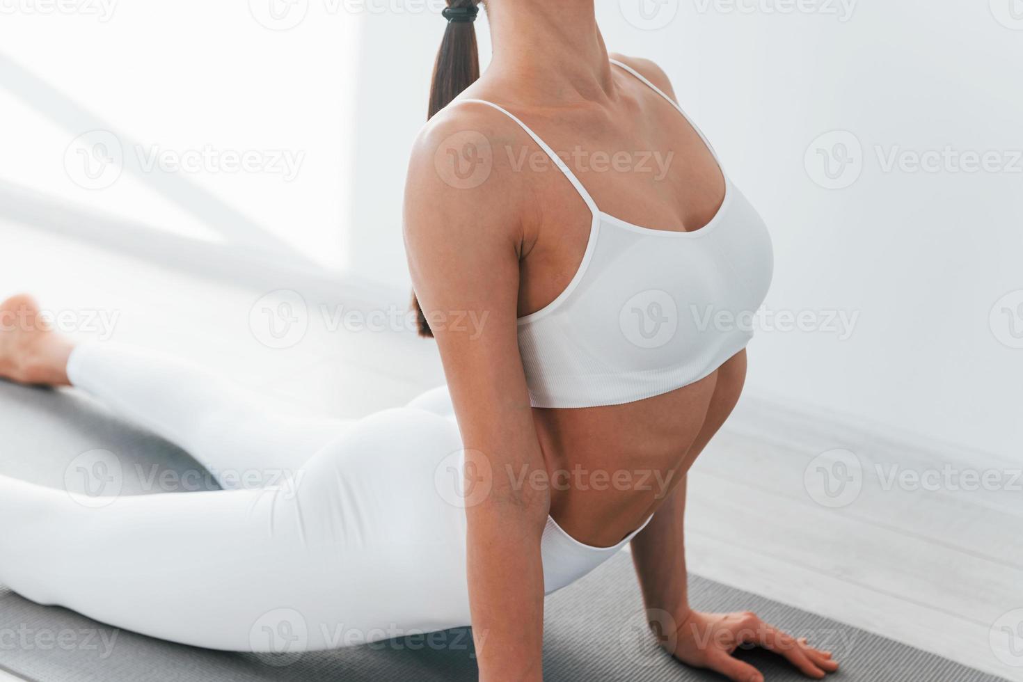 On yoga mat. Young caucasian woman with slim body shape is indoors at  daytime 15363172 Stock Photo at Vecteezy