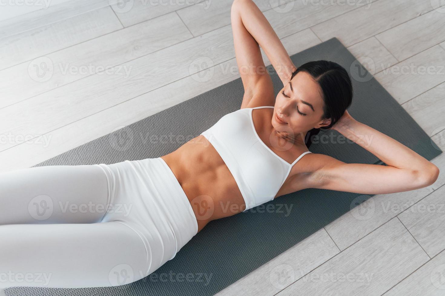 On yoga mat. Young caucasian woman with slim body shape is indoors at  daytime 15363172 Stock Photo at Vecteezy