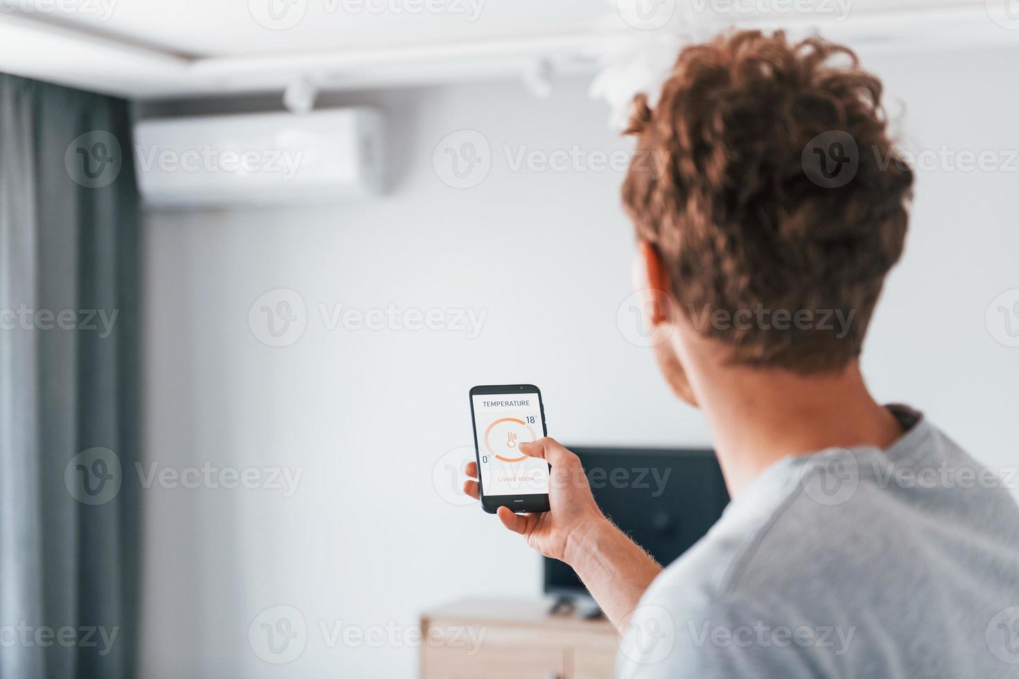 Rear view of adult man that is indoors controlling smart home technology photo