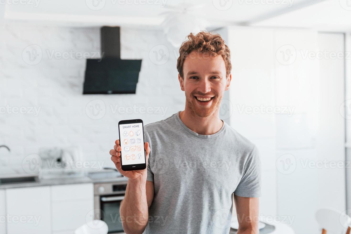 Young man in casual clothes is indoors controlling smart home technology photo