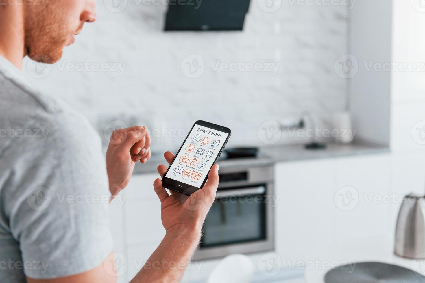 Rear view of adult man that is indoors controlling smart home technology photo
