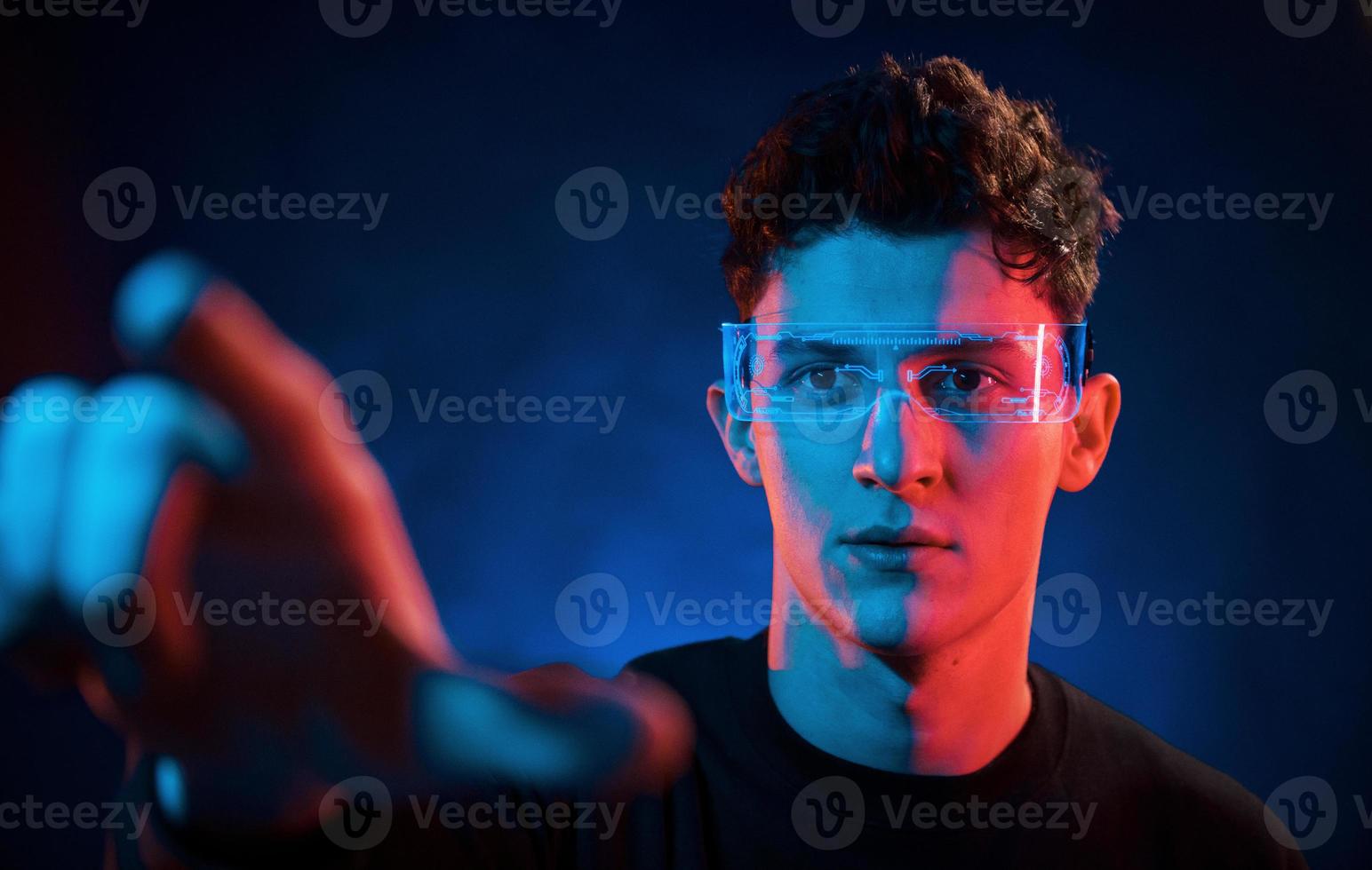 Close up portrait. Neon lighting. Young european man is in the dark studio photo