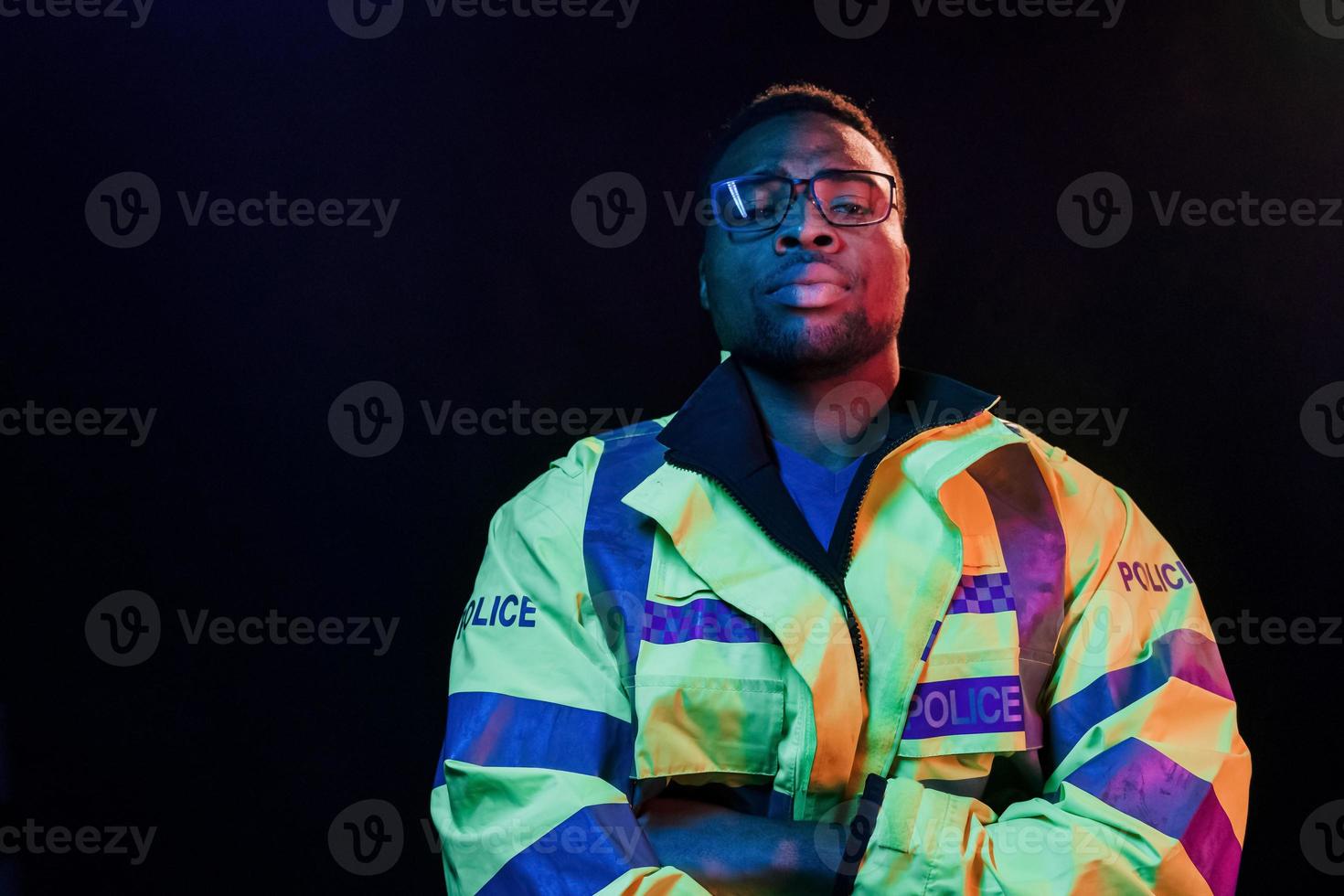 In police uniform. Futuristic neon lighting. Young african american man in the studio photo