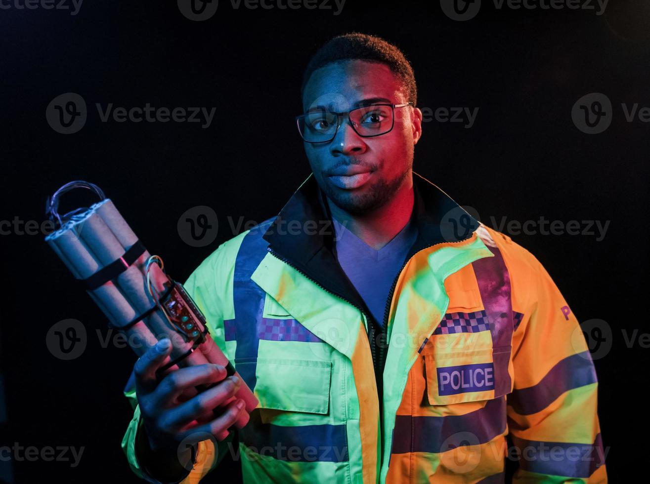 Policeman with bomb. Futuristic neon lighting. Young african american man in the studio photo