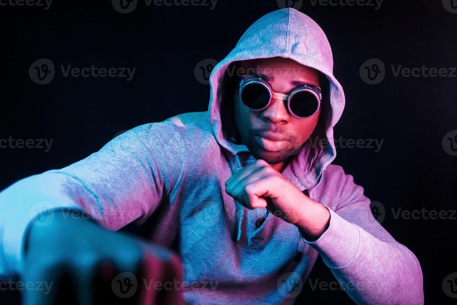 Cyberpunk style glasses. Futuristic neon lighting. Young african american man in the studio photo