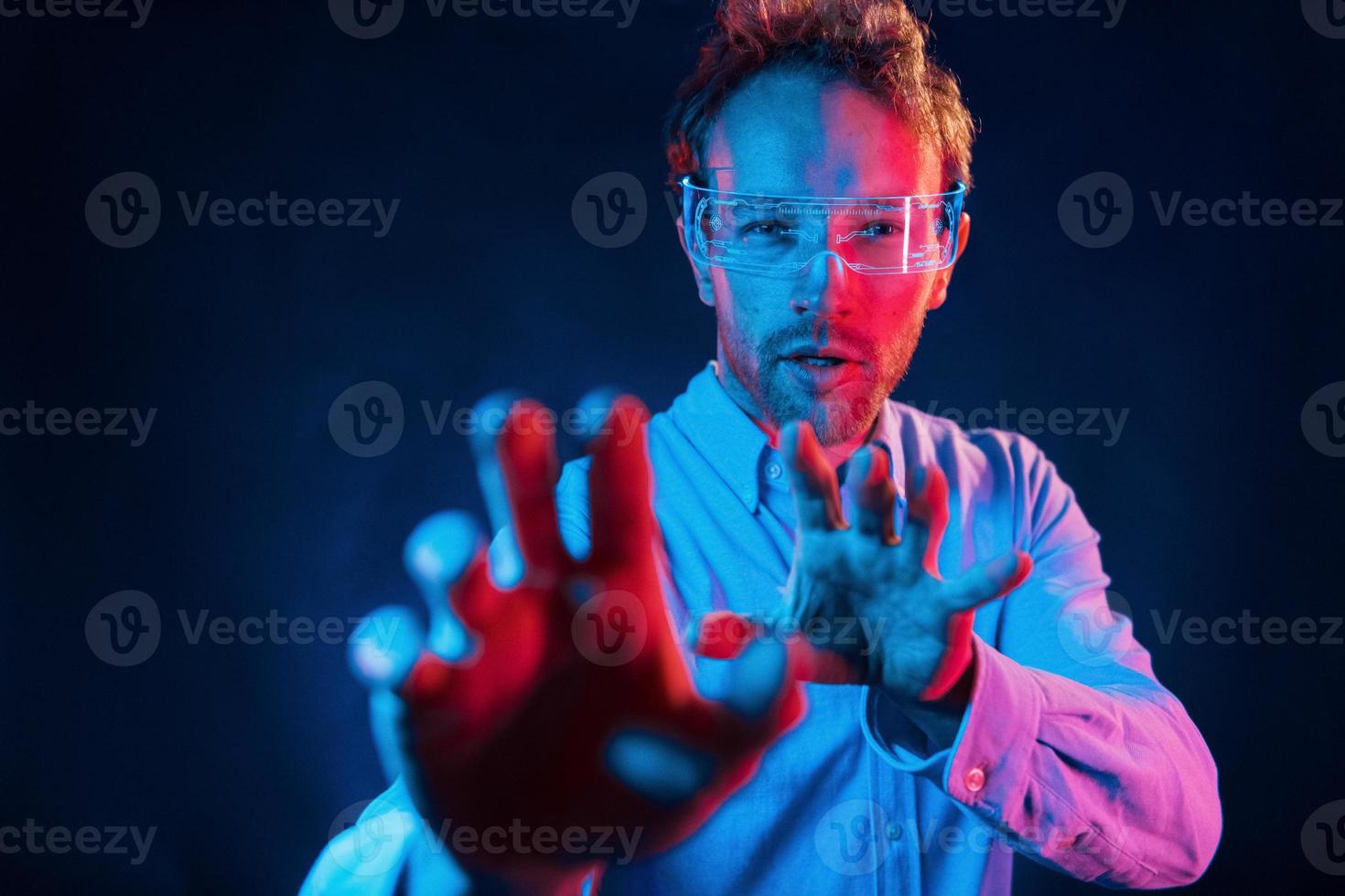 Virtual reality concept. Neon lighting. Young european man is in the dark studio photo