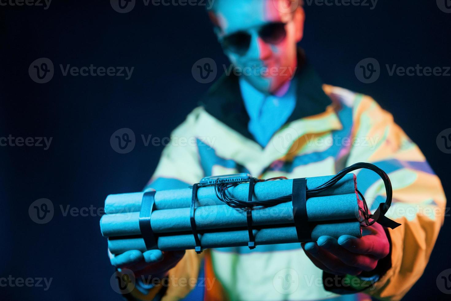 In police uniform. Neon lighting. Young european man is in the dark studio photo