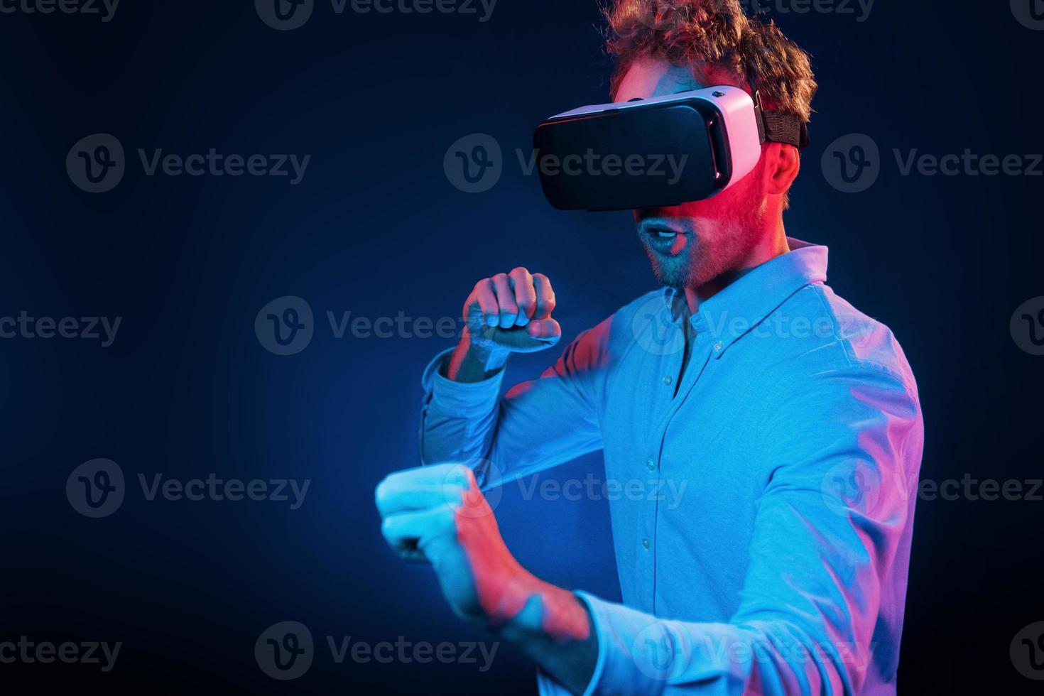 experiencia de juego de gafas virtuales. iluminación de neón joven europeo está en el estudio oscuro foto