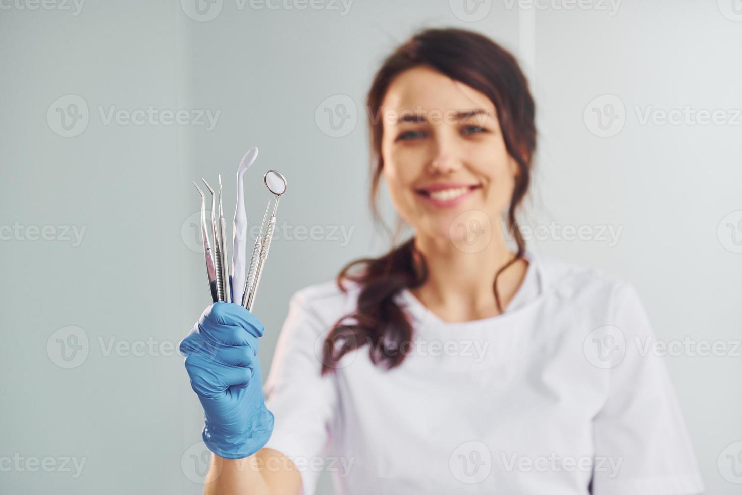 Portrait of professional female dentist with equipment that standing indoors photo