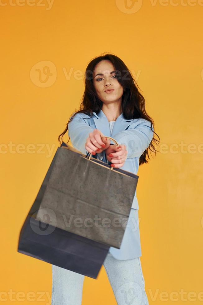 con bolsas de compras. mujer europea en ropa elegante de moda está posando en el interior foto