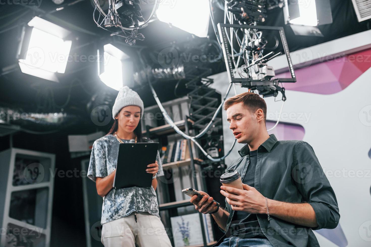 Young man is preparing for TV online broadcast. Woman helps with make up photo