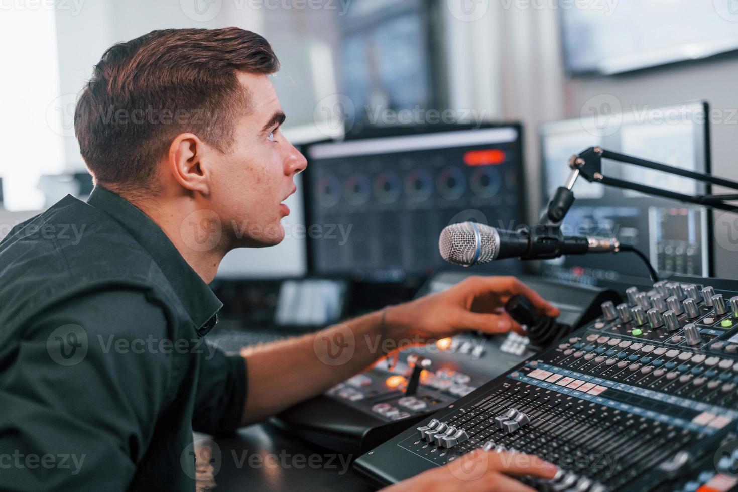 Young man is indoors in the radio studio is busy by broadcast photo