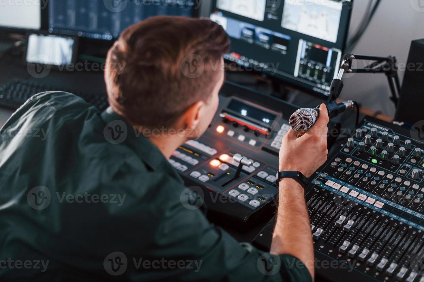 Setting the equipment. Young man is indoors in the radio studio is busy by broadcast photo