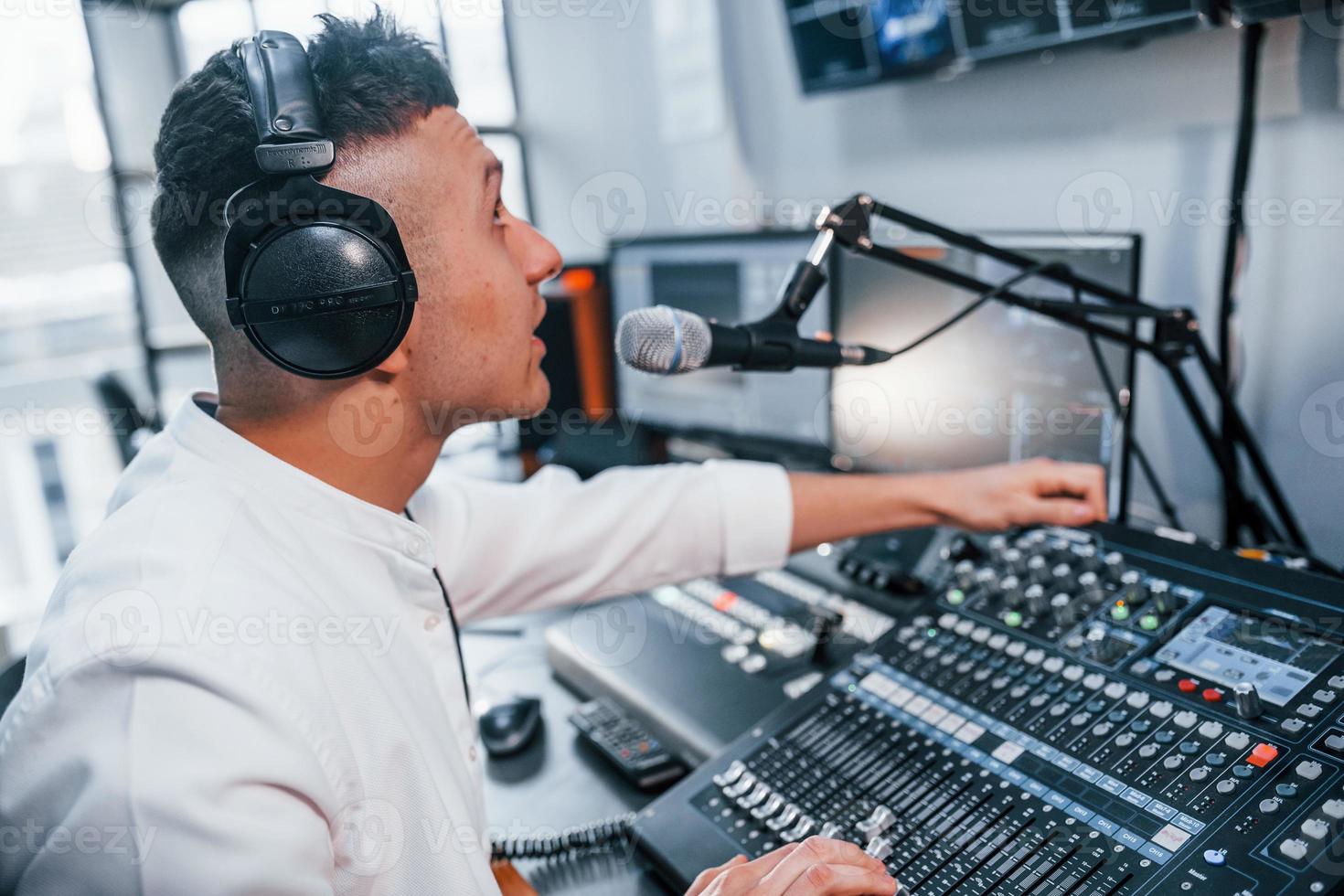 Setting the equipment. Young man is indoors in the radio studio is busy by broadcast photo