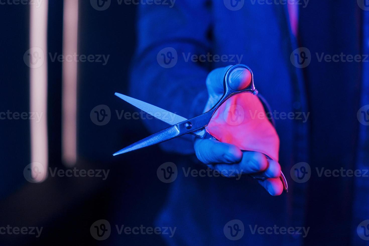 Close up view of barber's hands that holding scissors. Neon lighting photo