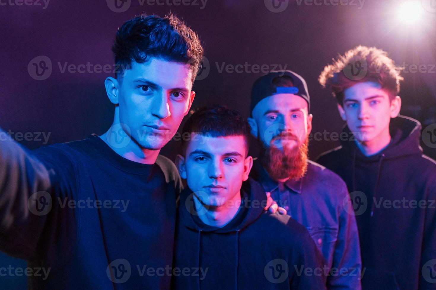 Taking selfie. Group of people is together in the studio with futuristic neon lighting photo