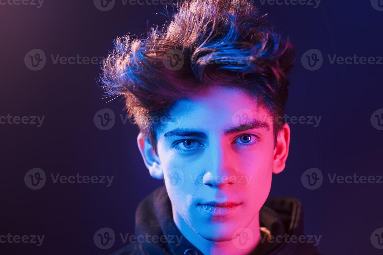 Portrait of young beautiful guy with fashionable haircut. Neon lighting photo