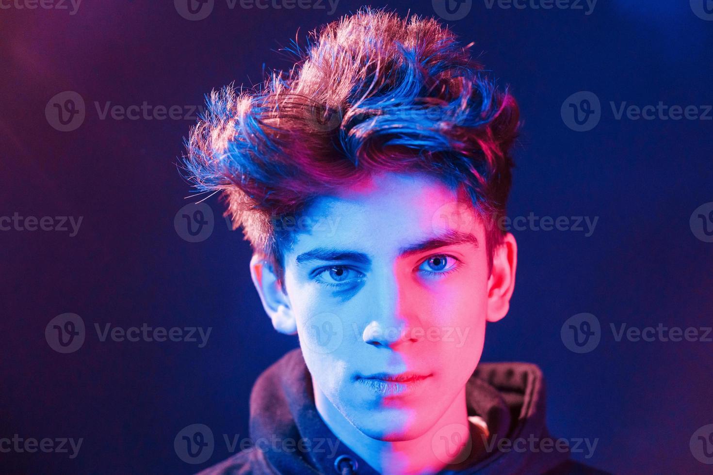 Portrait of young beautiful guy with fashionable haircut. Neon lighting photo