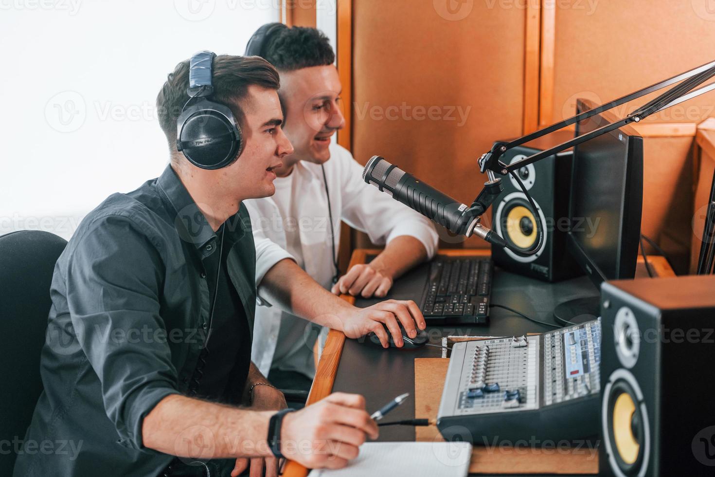 Two guys is indoors in the radio studio is busy by broadcast photo