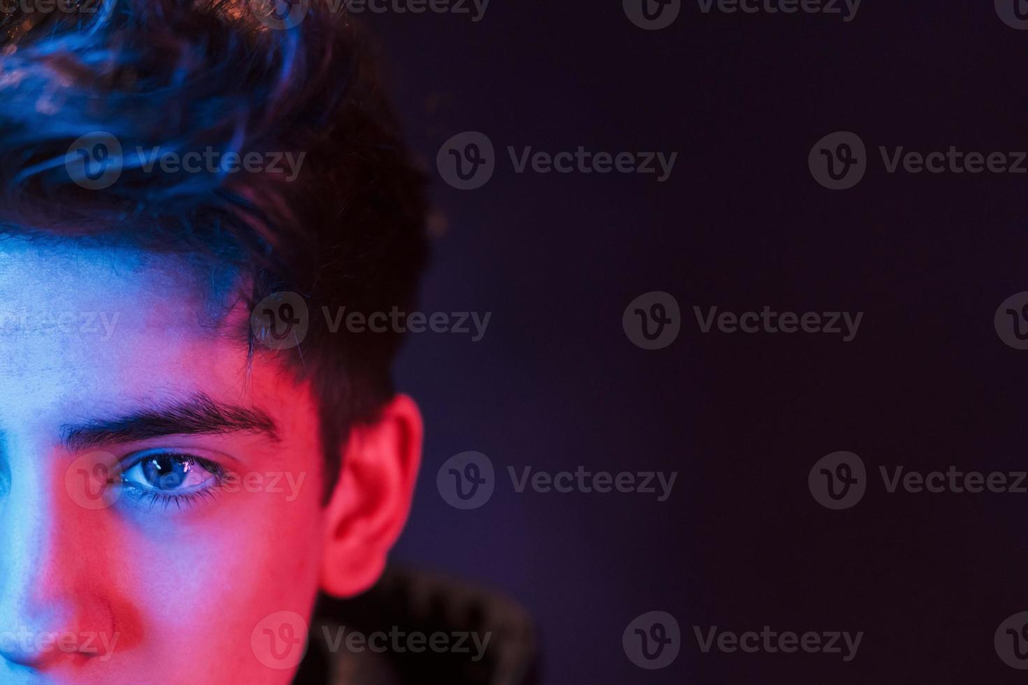 Portrait of young beautiful guy with fashionable haircut. Neon lighting photo