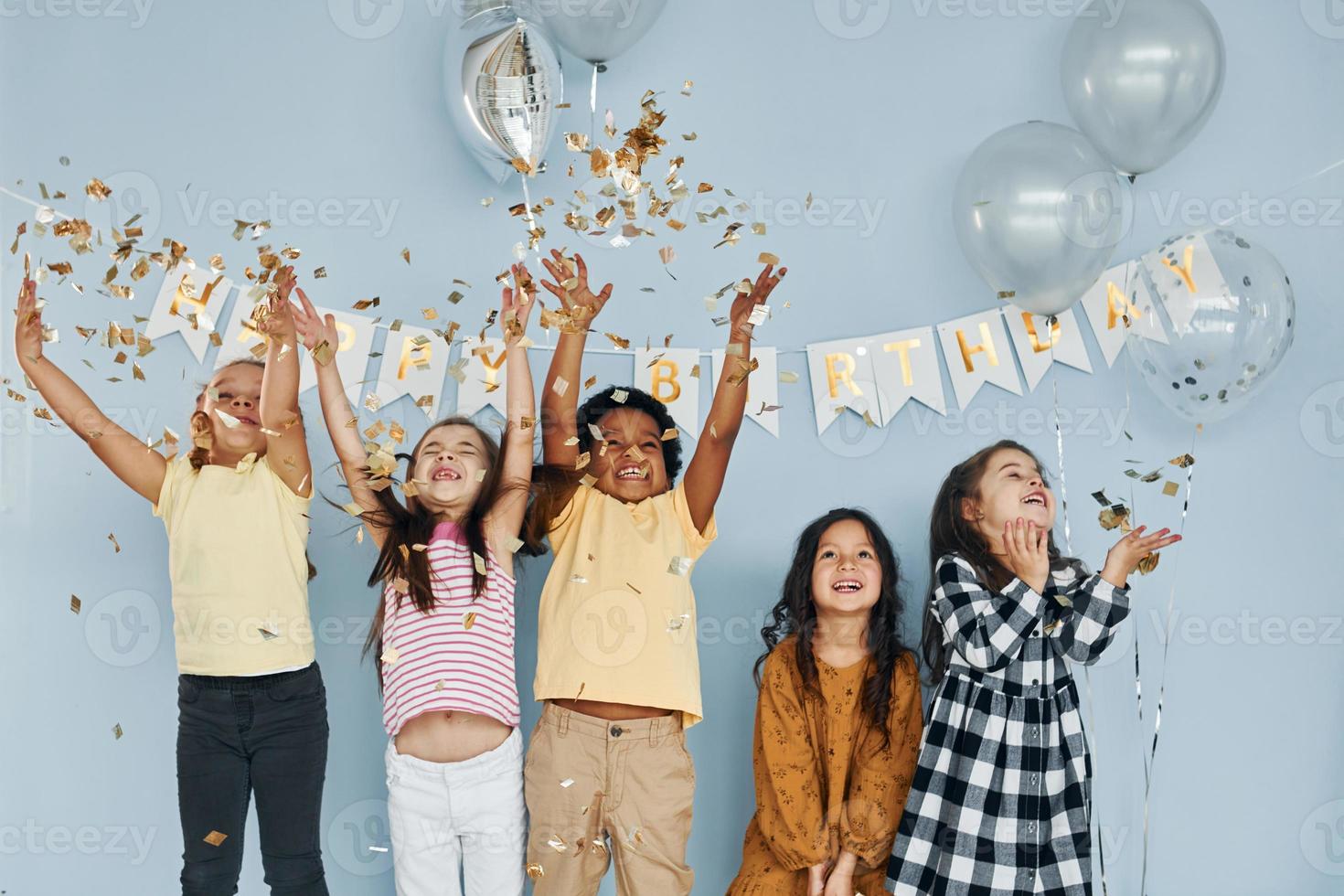 Balloons and confetti. Children on celebrating birthday party indoors have fun together photo