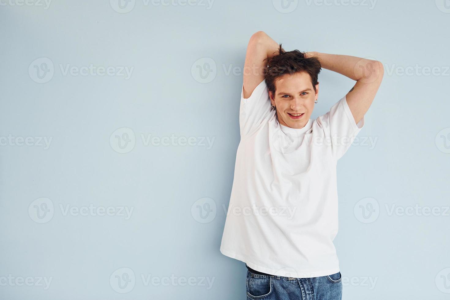 Young gay man is standing in the studio and posing for a camera photo