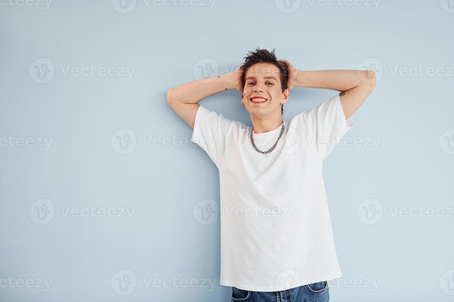 Young gay man is standing in the studio and posing for a camera photo