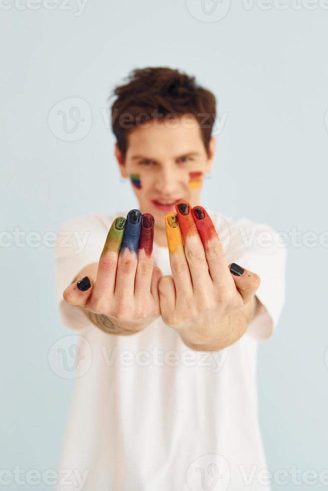 Young gay man is standing in the studio and posing for a camera. Shows gestures photo