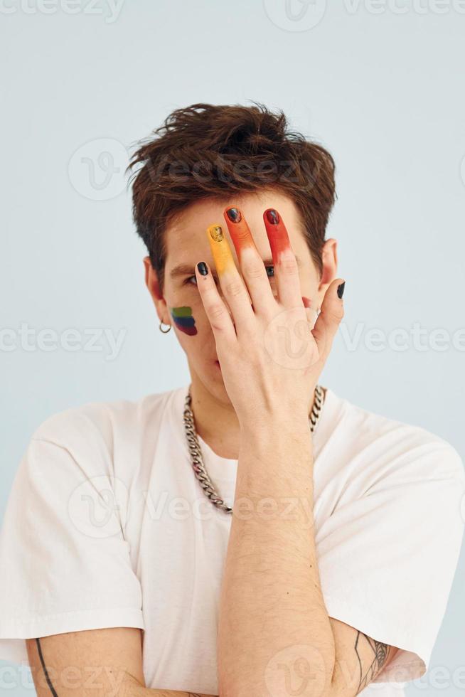 Young gay man is standing in the studio and posing for a camera. Shows gestures photo